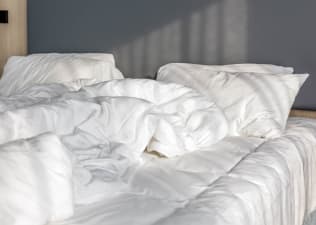 Scandinavian sleep method: Messy white blankets on a bed.