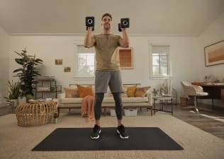 Man holds weights during a workout at home