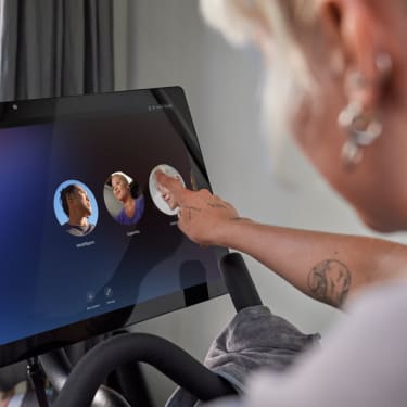 A woman exercising using the Peloton Bike and App in their home