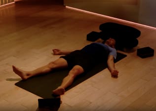 Denis Morton meditating and practicing savasana while lying down.