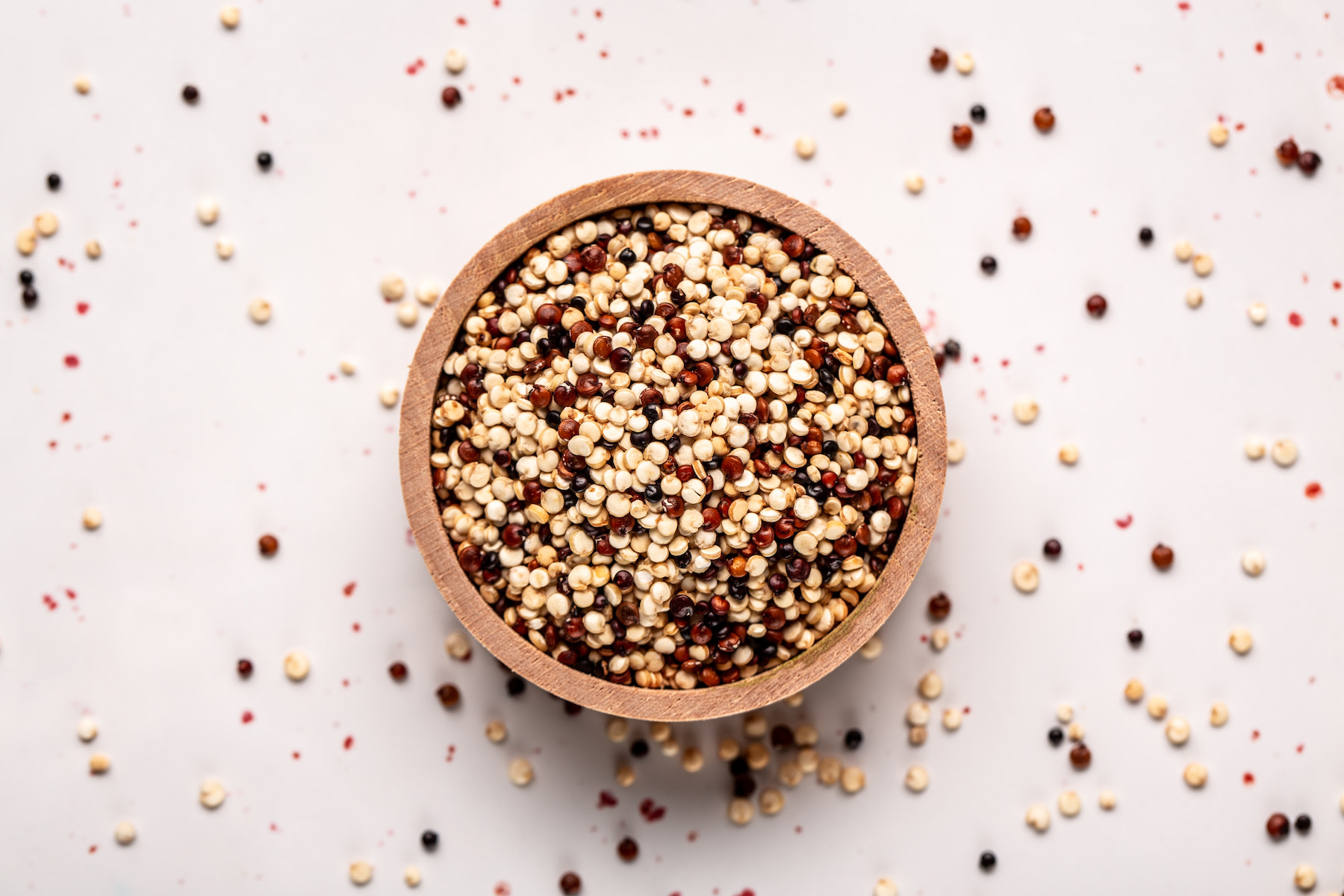 High-Fiber Foods: A bowl of uncooked quinoa against a white background.