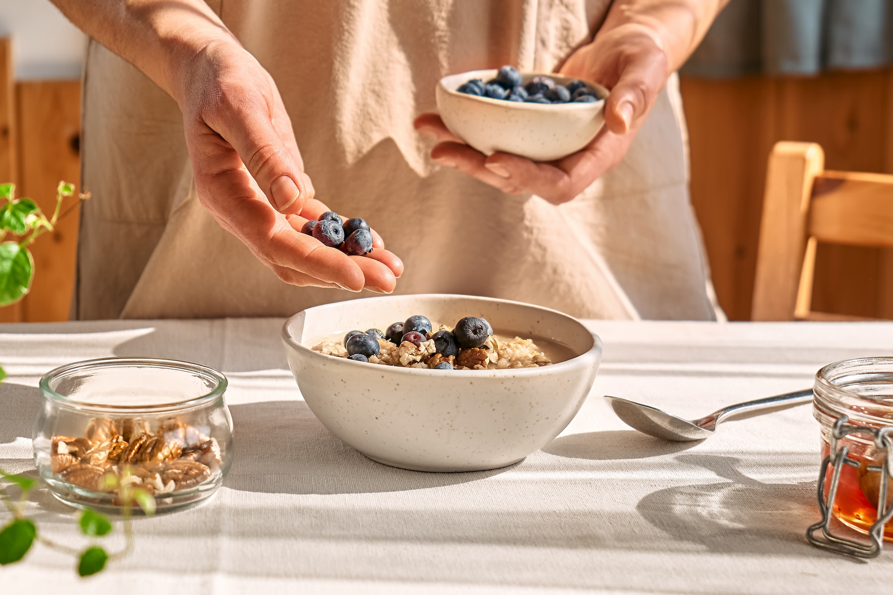 High-Fiber Foods: A person adding blueberries to a bowl of oatmeal.