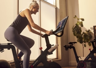 Woman cycles at home on Peloton Bike.