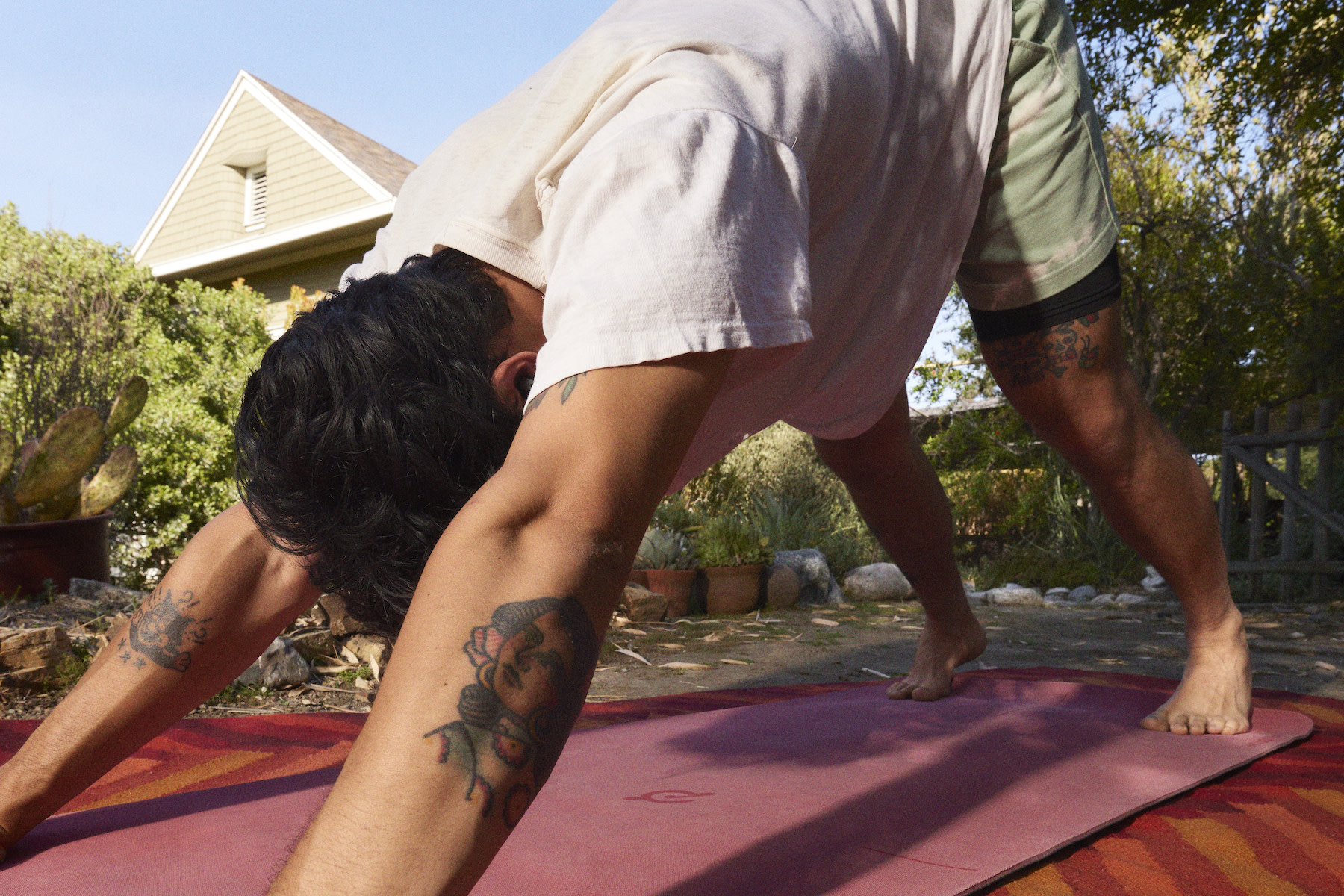 A man in Downward Dog pose on a clean yoga mat.