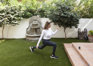 Woman does a walking lunge outdoors on grass