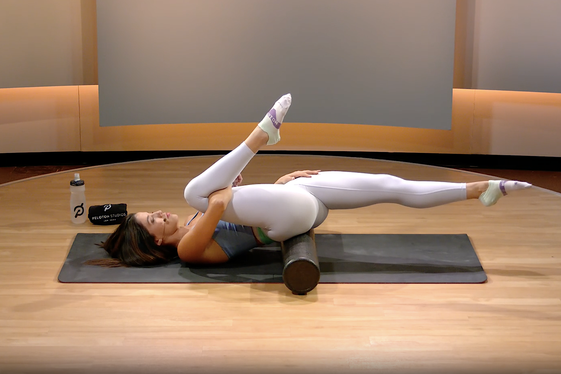Peloton instructor demonstrated front of hip and lower back release exercise on foam roller 